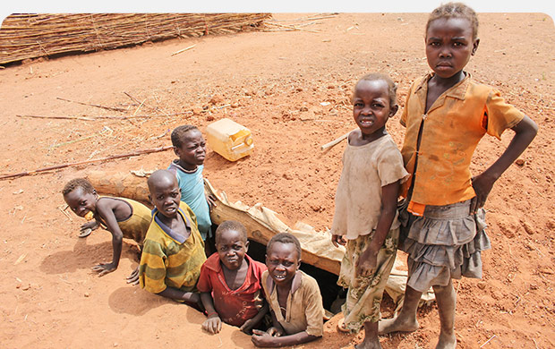 Children standing in and around a large hole