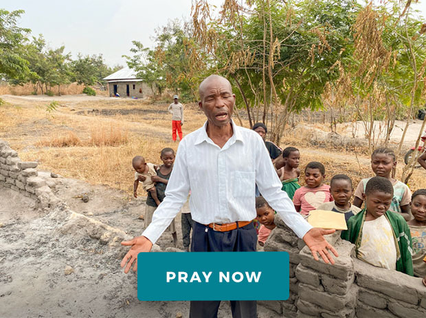 Pastor Pascal praying with children behind him